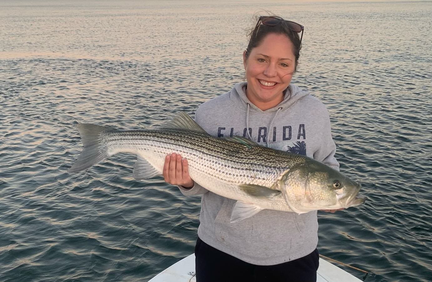 Angler holding a striped bass caught on the Long Island Sound with Captain Skippy Charters