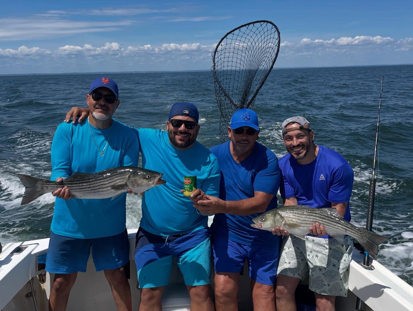 Three anglers in blue with striped bass and a landing net on the Christina M II