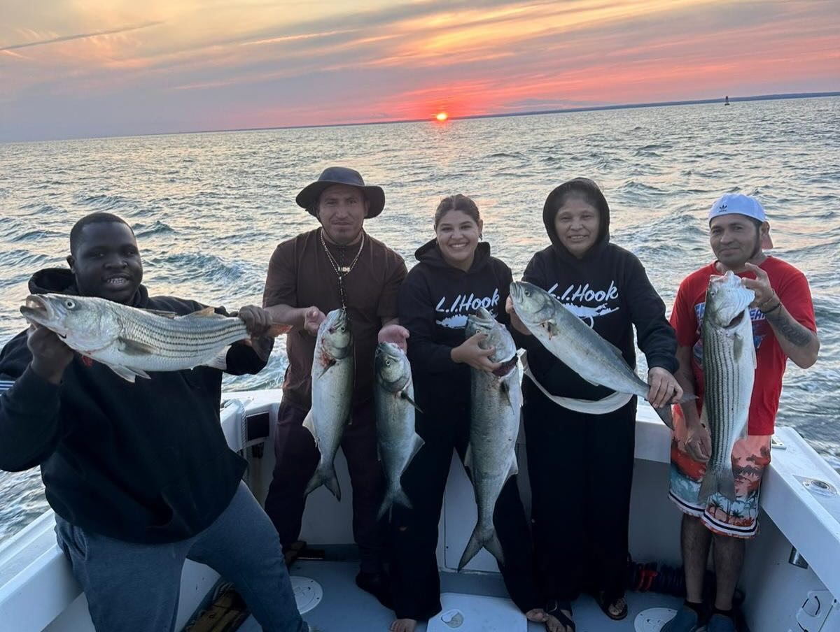 Group holding striped bass at sunset on the Long Island Sound