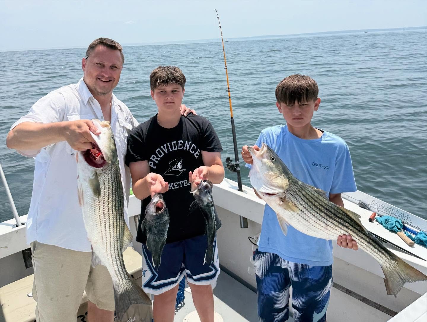 Father and sons with striped bass on a family fishing charter out of Mount Sinai
