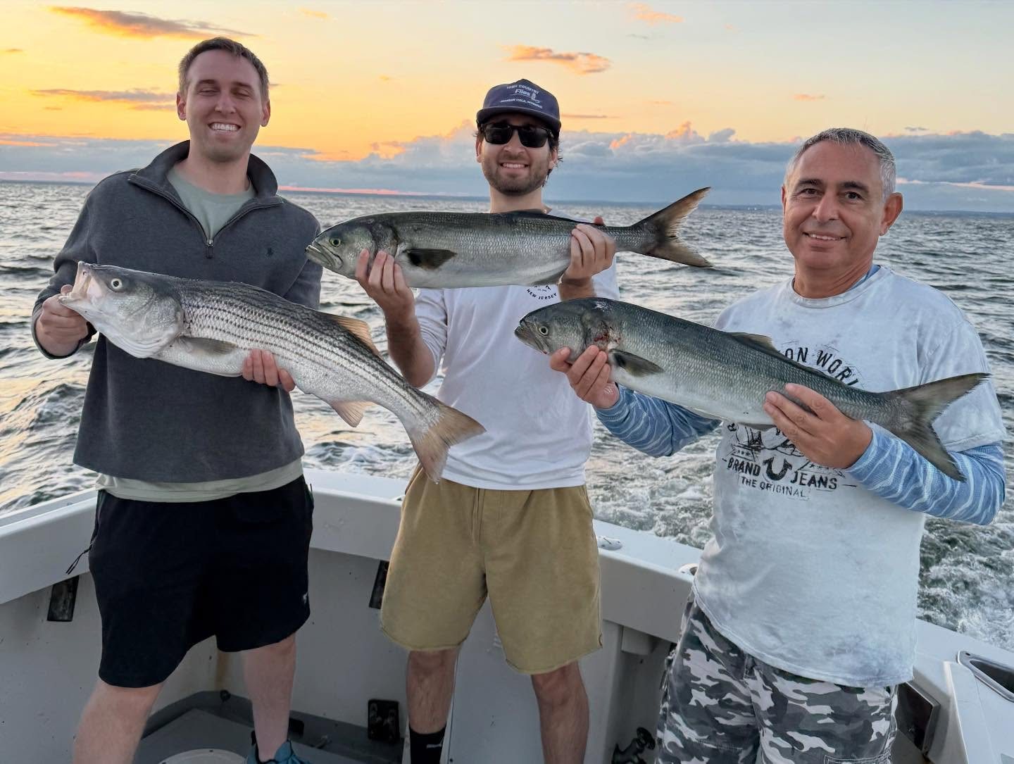 Three anglers with striped bass and bluefish on the Long Island Sound