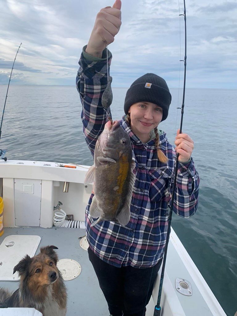 Young angler with a catch and the boat dog aboard the Christina M II