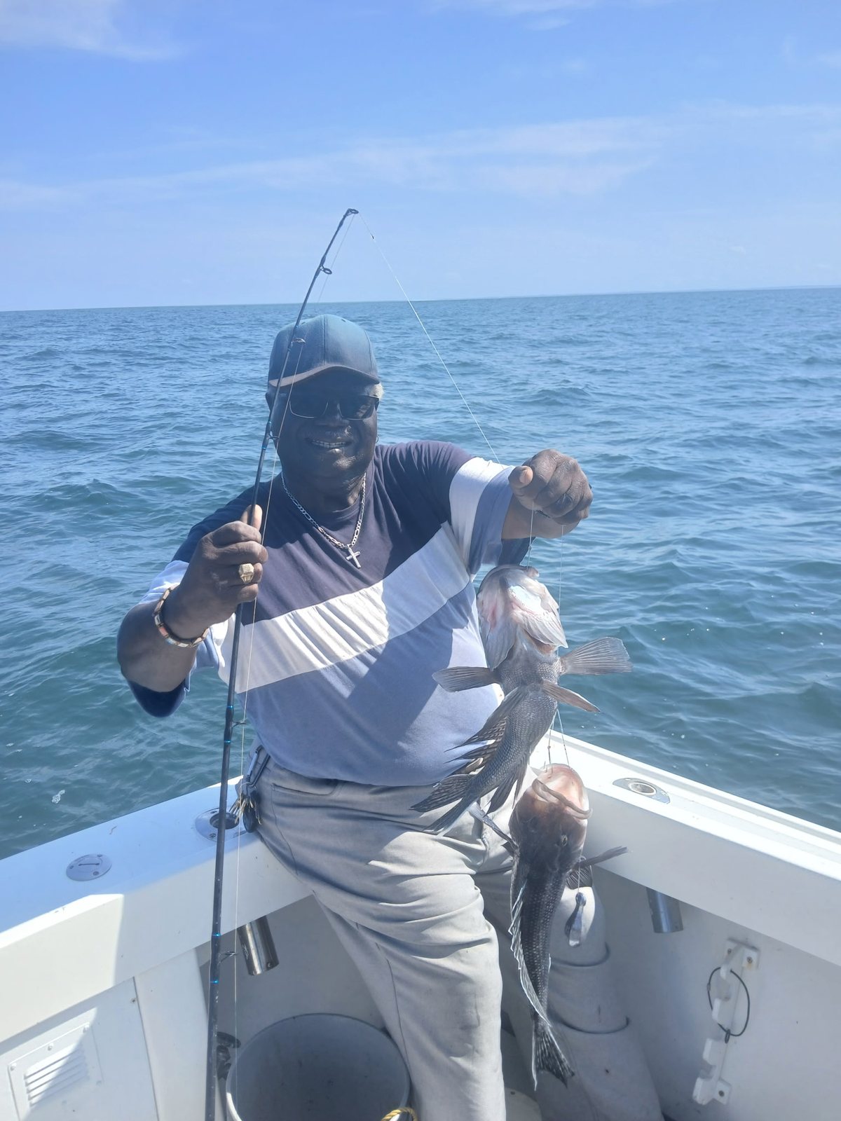 Angler with sun protection holding a fish on a summer Long Island Sound charter