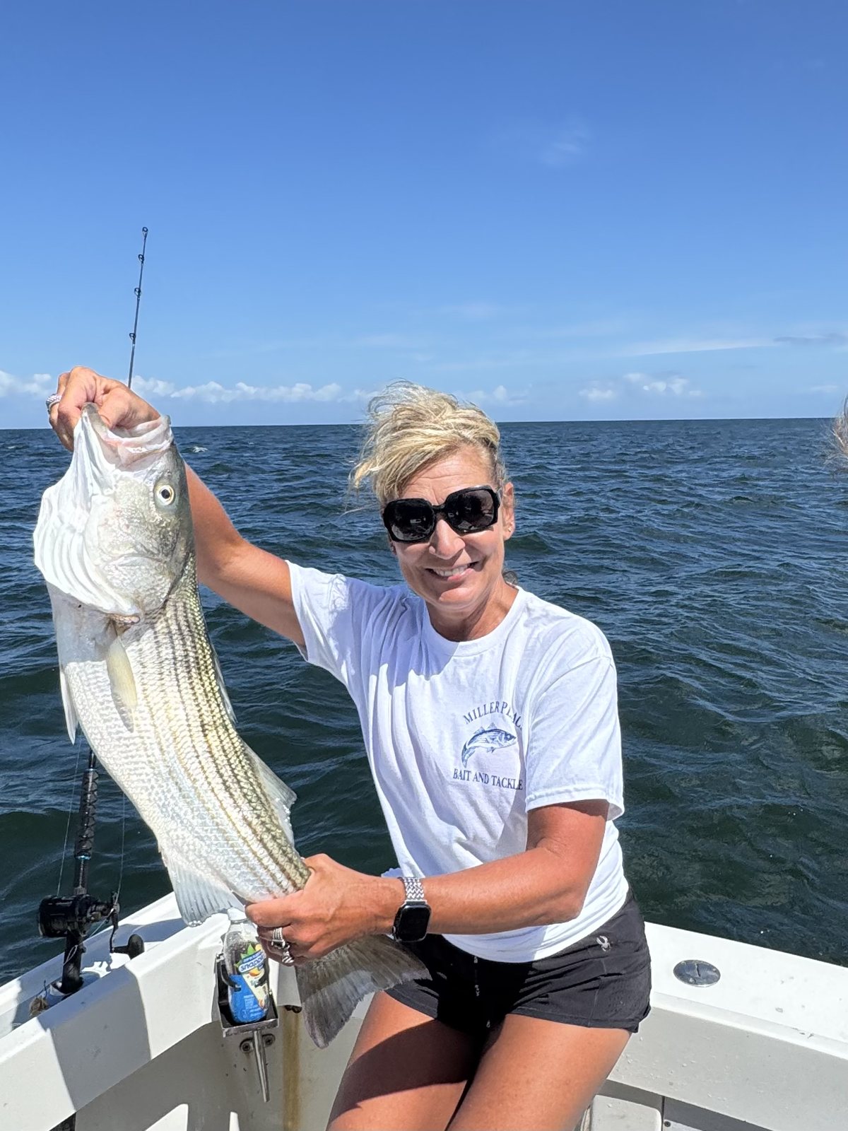 Angler in sunglasses holding a striped bass on the Long Island Sound