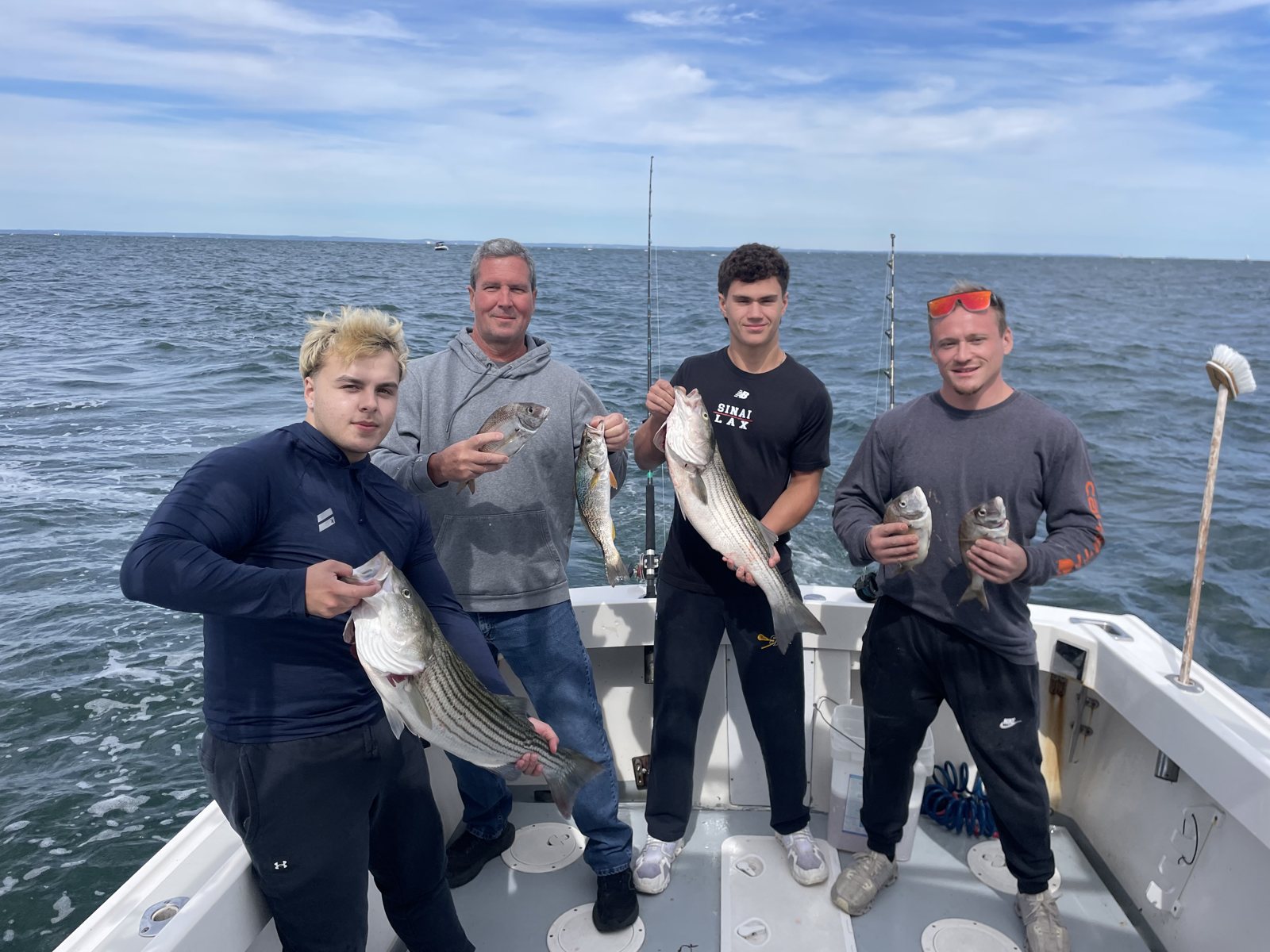 Three young anglers holding striped bass on the Christina M II