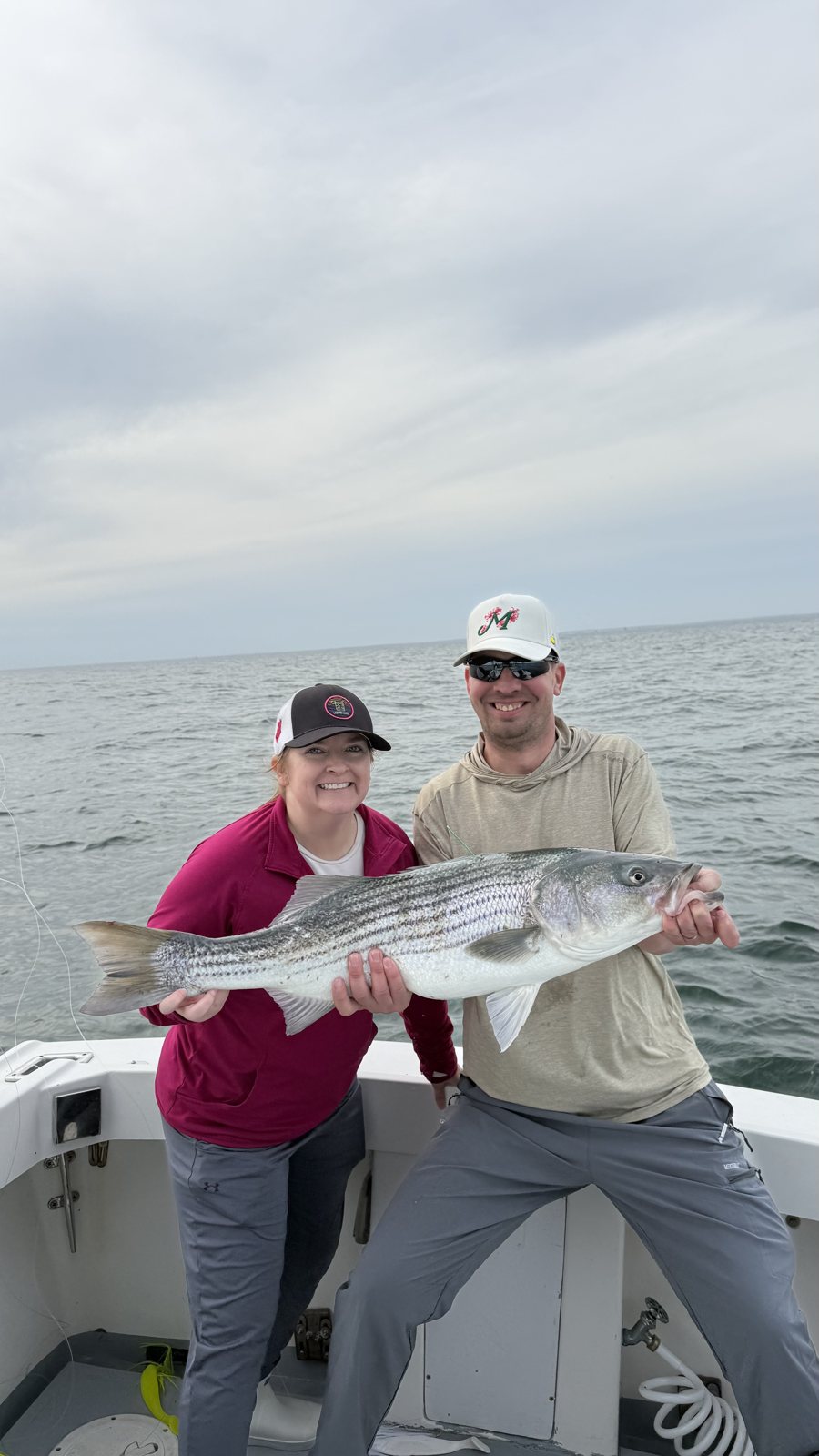 Two anglers with a striped bass on a private charter out of Mount Sinai