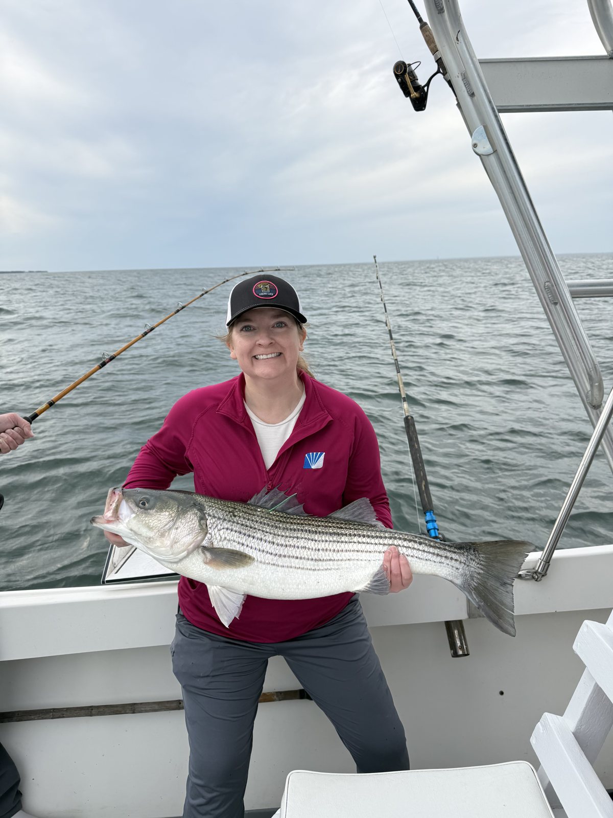 Angler in red holding a striped bass on the Long Island Sound