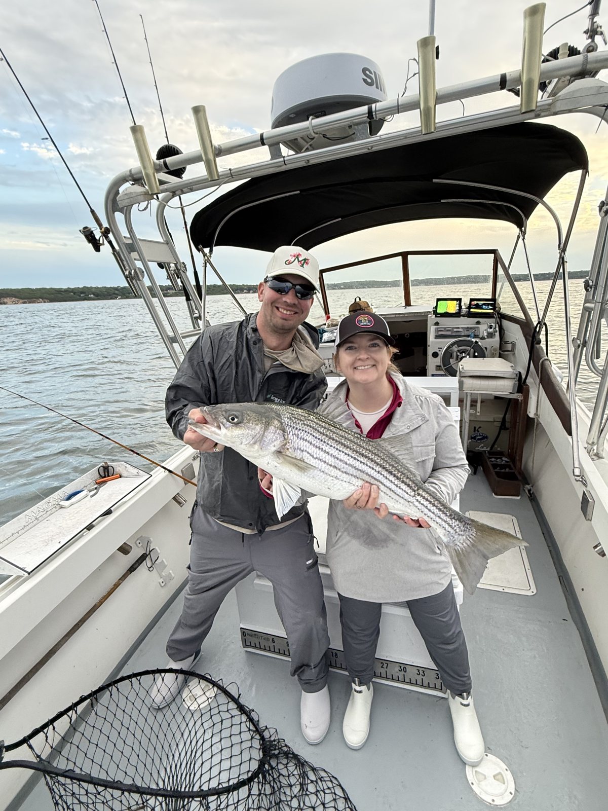 Couple holding a striped bass together on a Christina M II charter