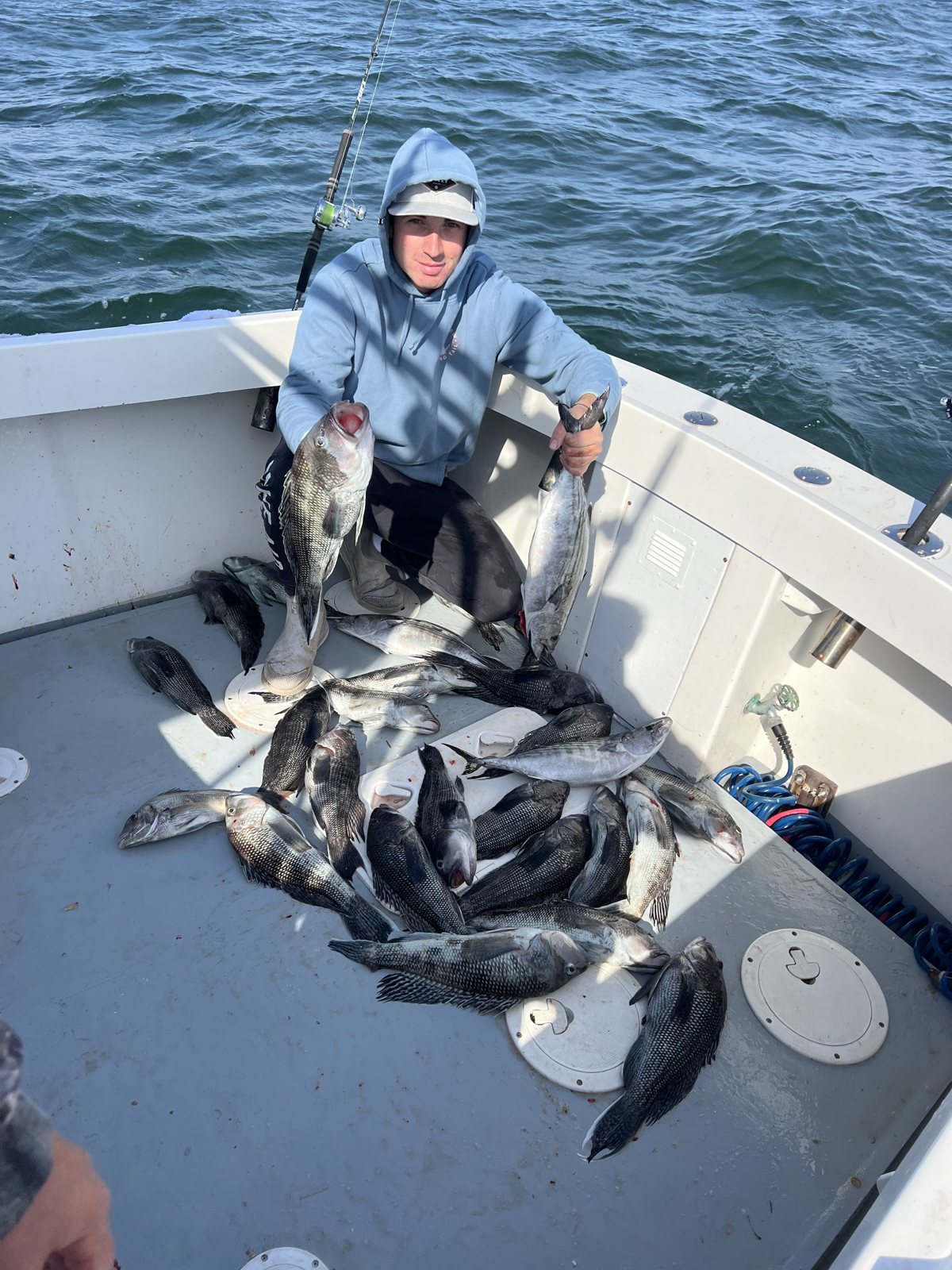 Young angler beside a deck haul of blackfish and sea bass on a fall charter