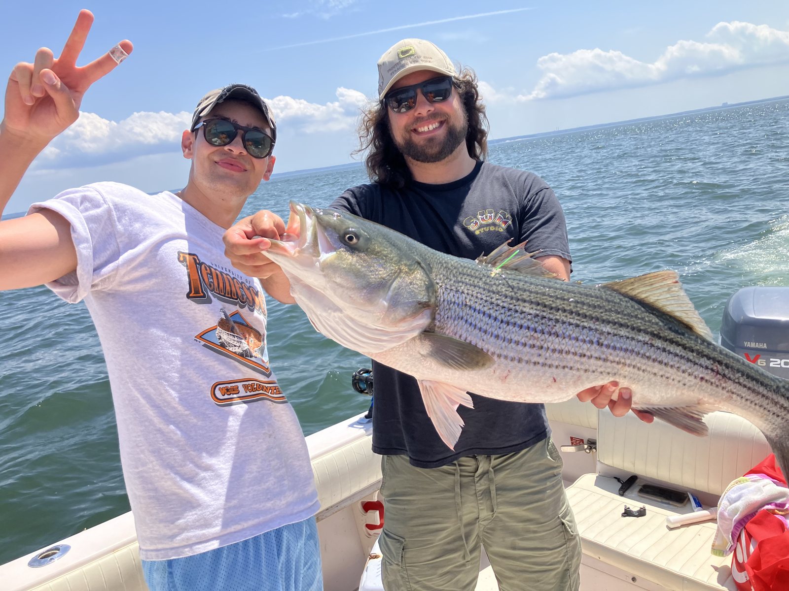 Two anglers holding striped bass on a Long Island Sound charter