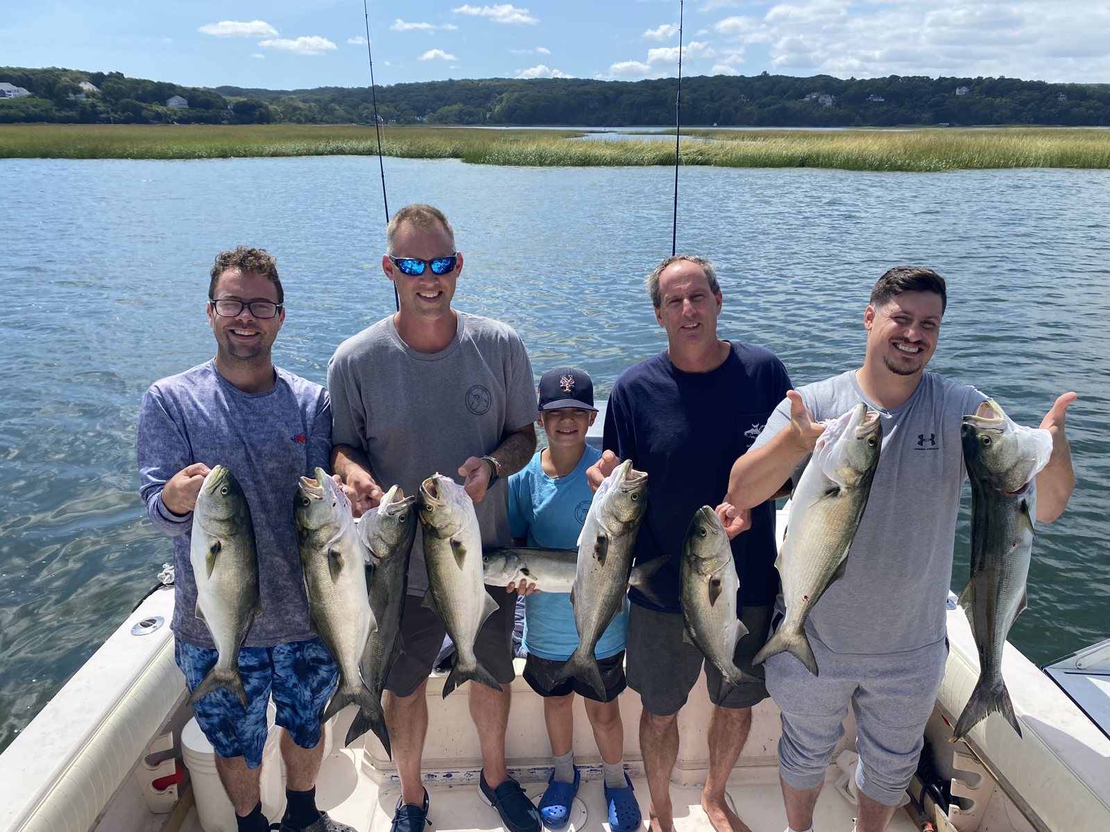 Anglers with striped bass and the Long Island shoreline behind them